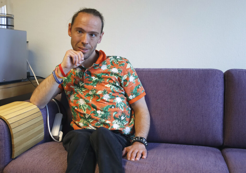 Erik Dahlström sitter i sin lila soffa. Han vilar sin arm på armstödet, och håller sin hand på sin haka.