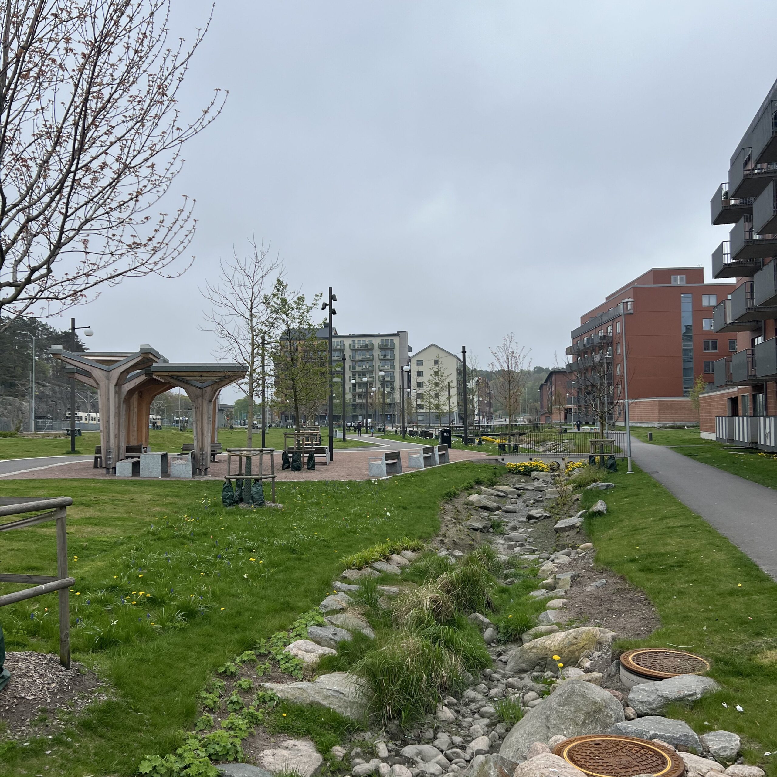 Ett stenigt dike som sträcker sig mot ett bostadsområde i bakgrunden. Till vänster en sittyta.