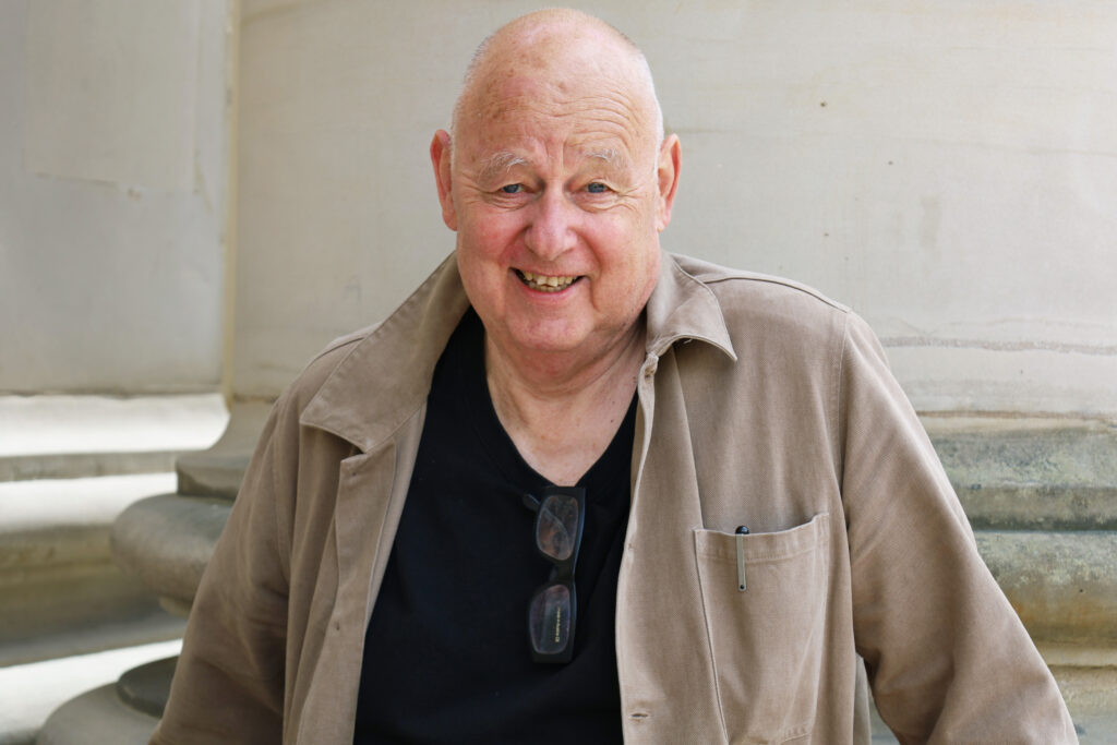 Gert Wingårdh, iklädd en beige jacka, ler mot kameran.