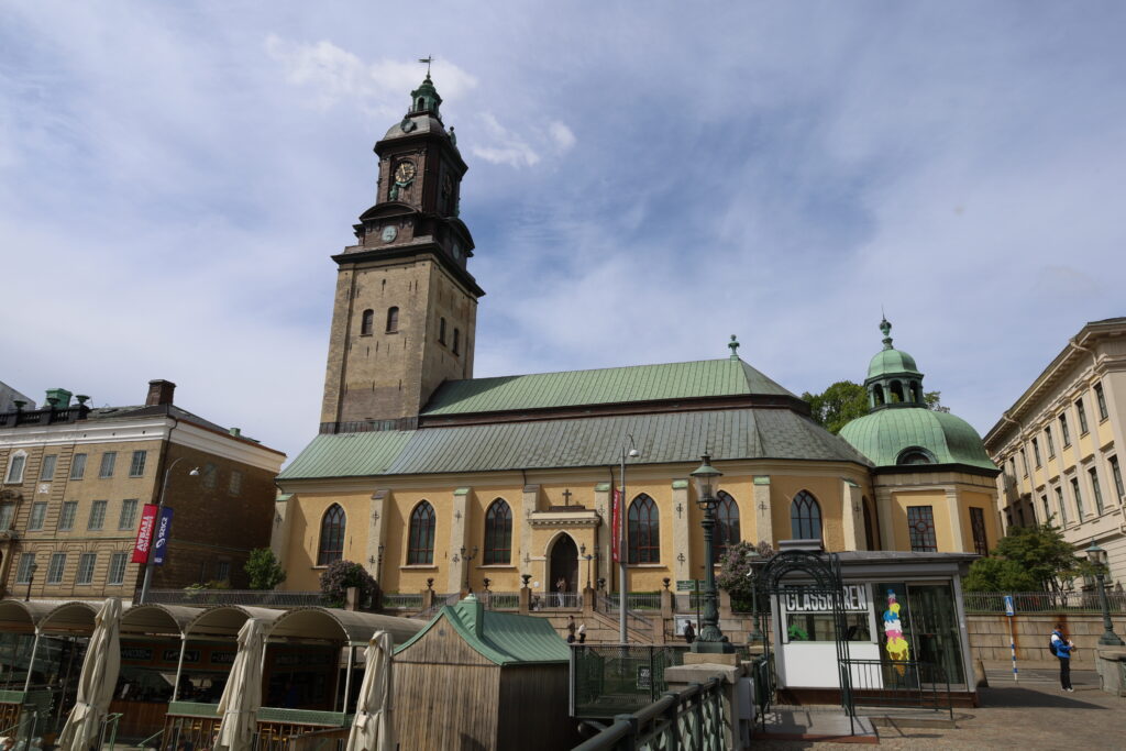 Tyska kyrkan med sin gula stenfasad, blågröna tak, och bruna klocktorn.