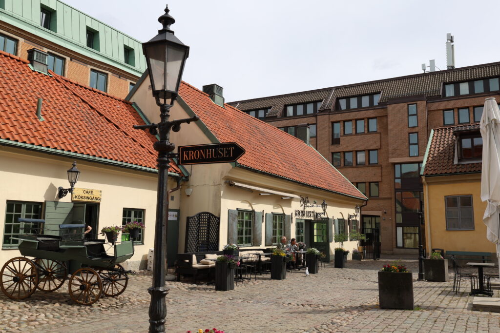 Hus med en ljust gul stenfasad och fönster med mörkt gröna fönsterluckor, samt tak i orange tegel.