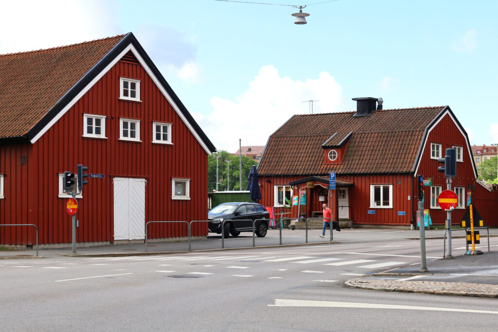 Röda trähus med bruna tegeltak, samt vita dörrar och fönster. 