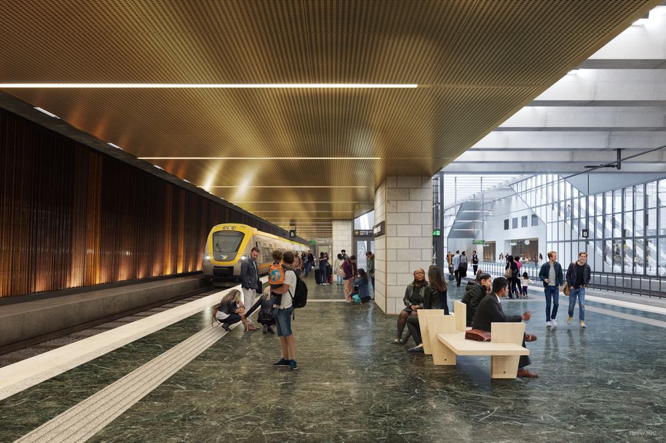 Illustration inifrån en tågstation. Människor rör sig runt på en plattform under ett metalltak, samtidigt som ett gult tåg rullar in parallellt med en brun vägg.